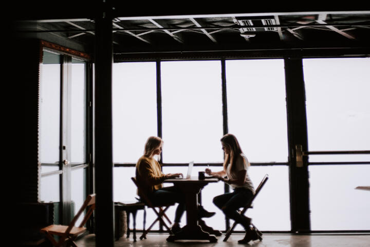 two people at a meeting desk silhouetted against a window in an creative workspace