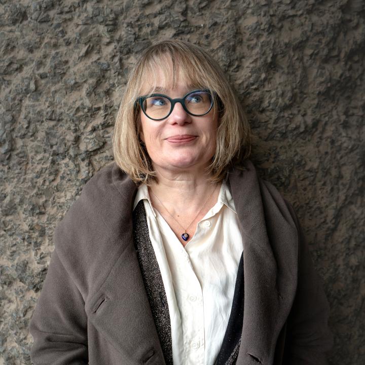 head and shoulders portrait against a textured concrete wall